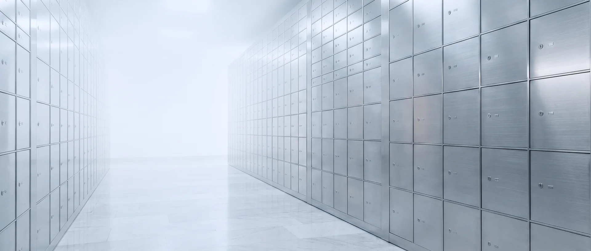 A corridor of brushed-steel safe-deposit boxes receding into soft white light